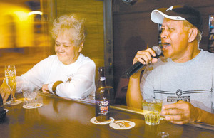 Nani Smythe of Kapahulu listens to Nu‘uanu resident Kani Kaimi sing a karaoke number at Smith's Union Bar on North Hotel Street. Photo by Rebecca Breyer • The Honolulu Advertiser